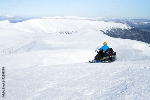 Man on snowmobile in winter mountain.