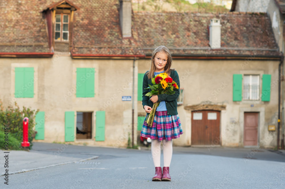 Outdoor portrait of a cute little girl with beautiful bouquet of flowers