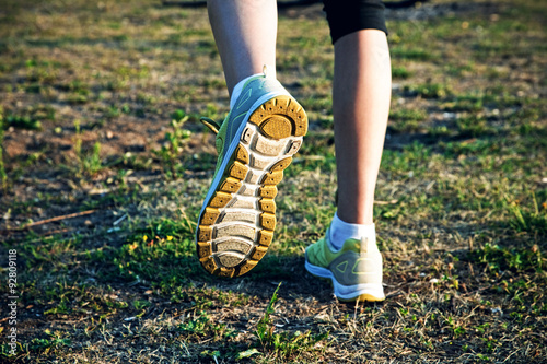 Girl jogging outside. Feet running on grass