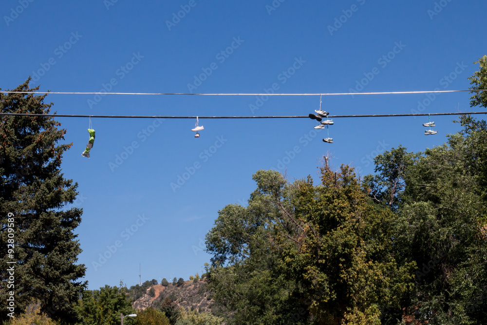 Multiple shoes hanging on a wire over a street