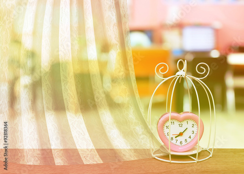 white lacework frame with bird cage and pink clock on blur offic