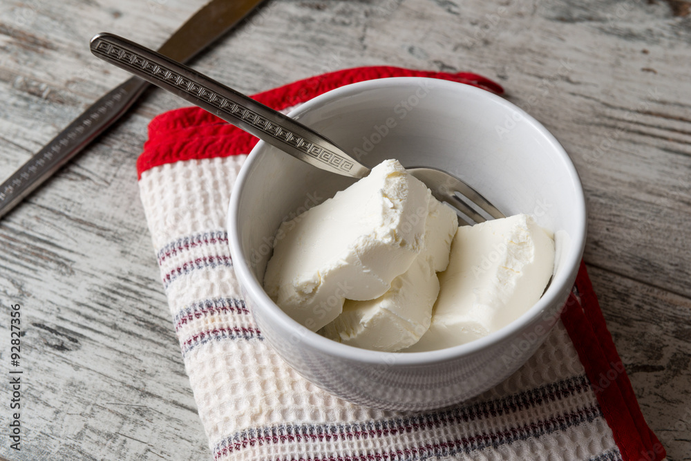Pezzi di formaggio cremoso in una tazza di ceramica bianca su un tavolo di legno Pezzi di formaggio cremoso in una tazza di ceramica bianca su un tavolo di legno