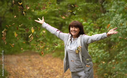 happy woman throws up autumn leaves