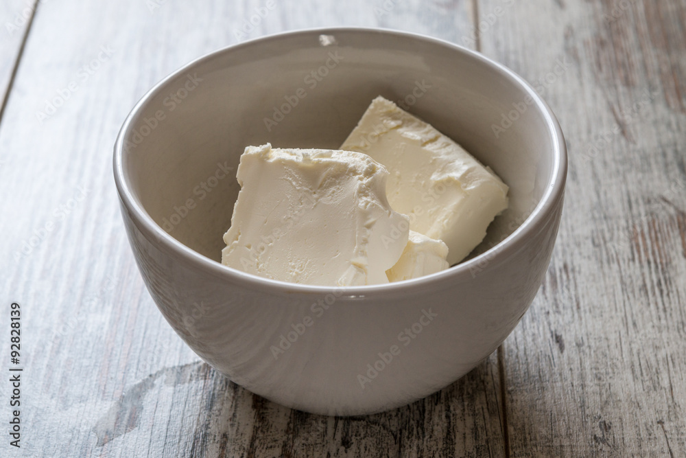 Pezzi di formaggio cremoso in una tazza di ceramica bianca su un tavolo di legno