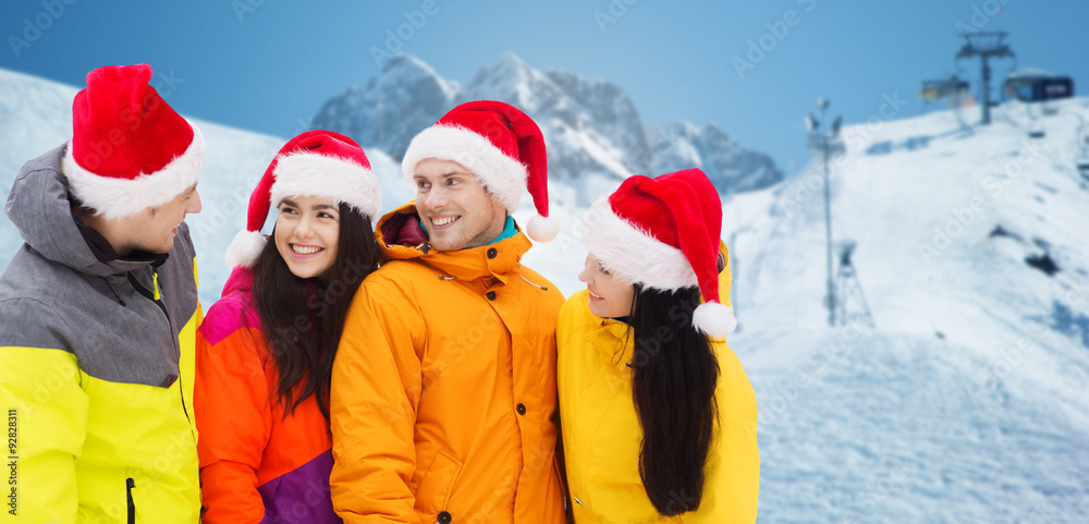 happy friends in santa hats and ski suits outdoors