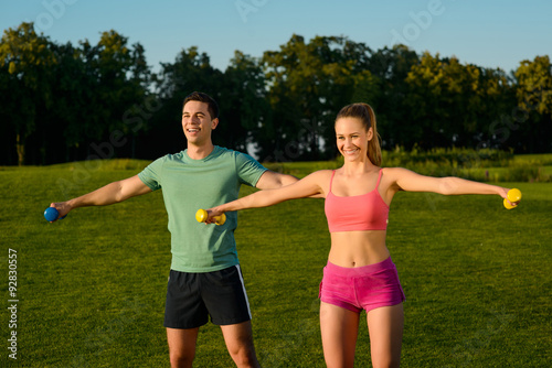 Guy with the girl shakes muscles  with dumbbells. © DenisProduction.com