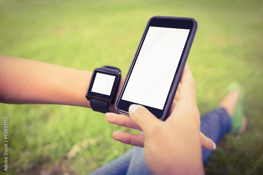 Cropped hands of person wearing smartwatch and holding smartphones