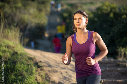 Athlete woman running in nature jogging path determined serious focused mental strength