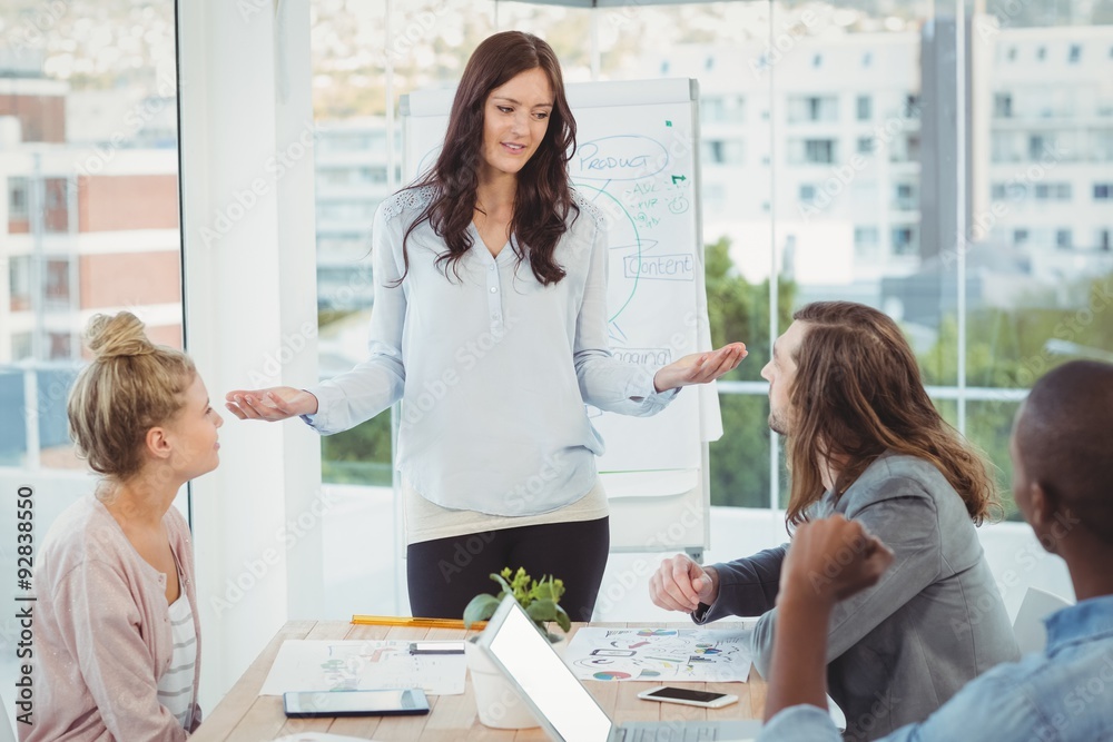 Woman gesturing while discussing with coworkers Woman gesturing while discussing with coworkers