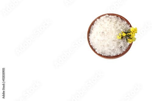 sea salt and yellow flowers in a wooden bowl isolated on white background