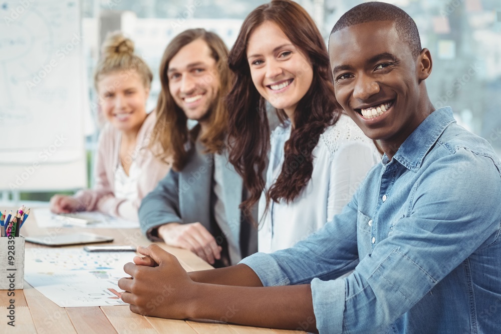 Portrait of smiling business people sitting in row at desk Portrait of smiling business people sitting in row at desk