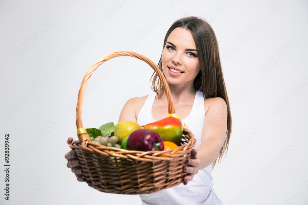 Fototapeta premium Girl giving basket with fruits at the camera