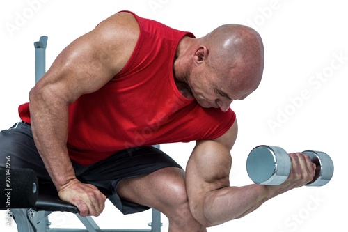 Bald man exercising with dumbbells while sitting on bench press