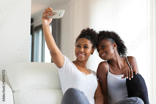African American teenage girls taking a selfie picture with a sm photo