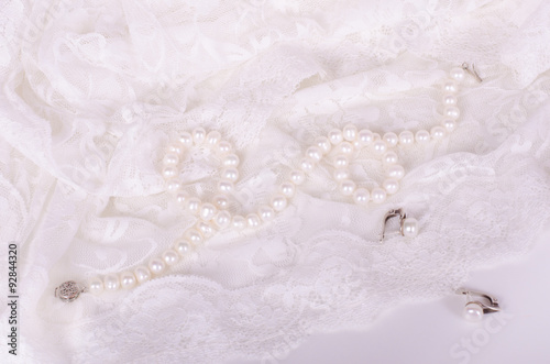 Pearl necklace and earrings on white lace cloth 
