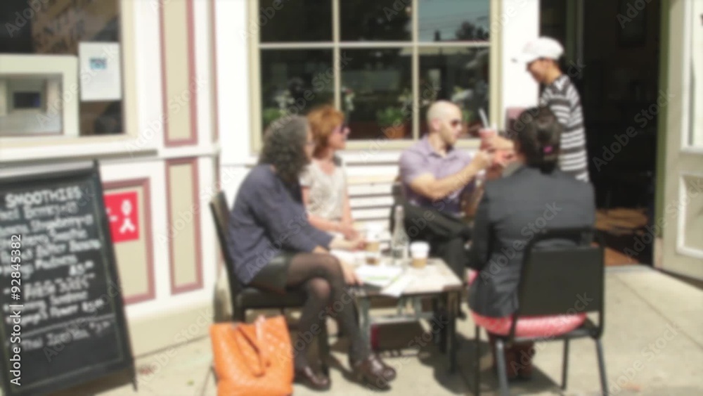 People sitting outside a small cafe on sidewalk People sitting outside a small cafe on sidewalk