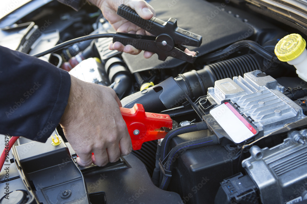 Close-Up Of Mechanic Attaching Jumper Cables To Car Battery Close-Up Of Mechanic Attaching Jumper Cables To Car Battery
