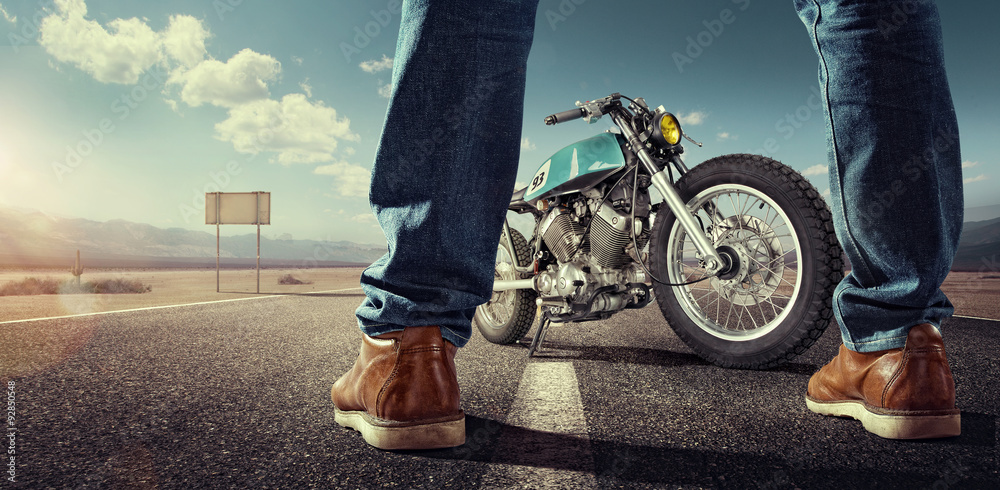 Obraz premium Sport. Rowerzysta stoi blisko motocyklu na pustej drodze przy słonecznym dniem. Zamknij widok na nogi