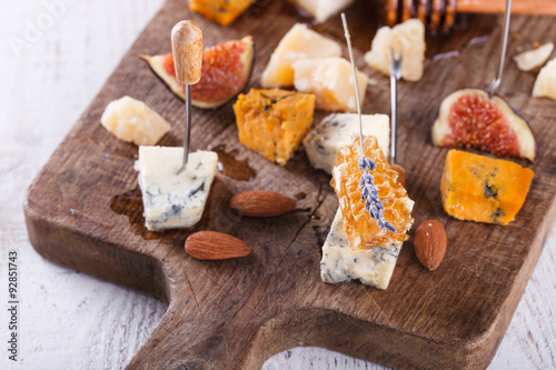 Grape, cheese, figs and honey with a glasses of red and white wine on a wooden Board. Cheese Board.selective focus