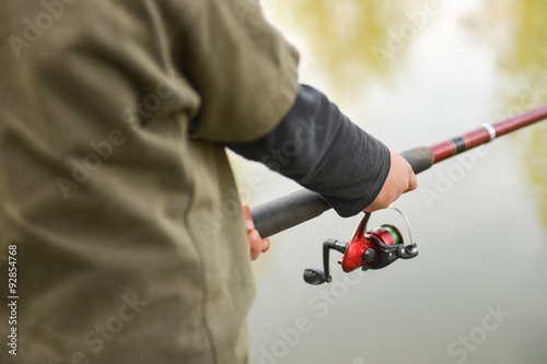 Closeup of fisherman`s hand holding rod with spinning. Fishing r
