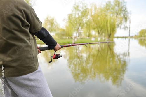 Closeup of fisherman`s hand holding rod with spinning. Fishing r