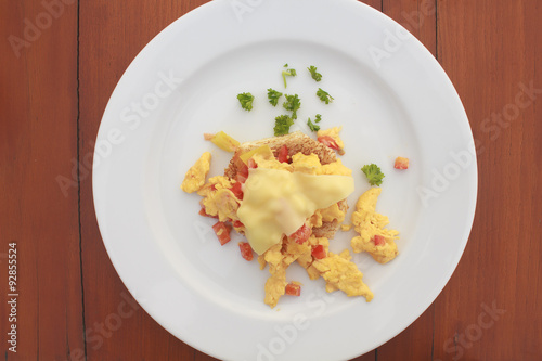 Scrambled egg with cheese and pancake in white dish on wooden table
