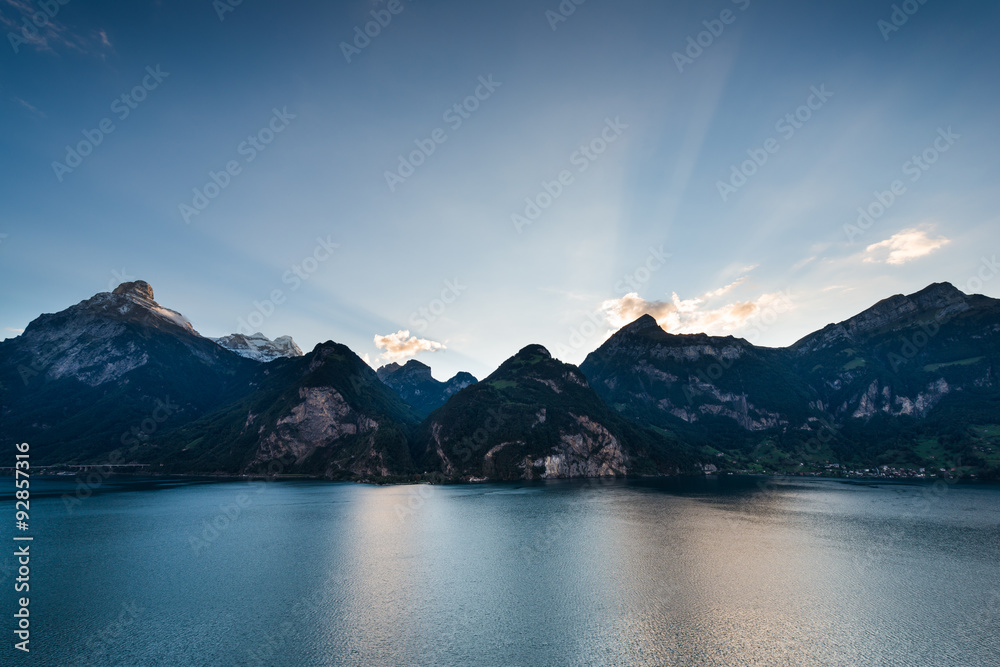 Magnificent panorama of mountains and lake in central Switzerland. Setting sun painted the clouds in the grand color. Wide lens