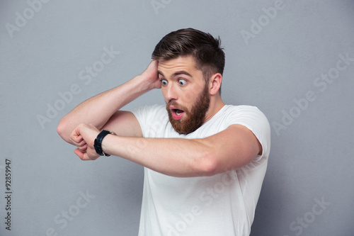 Shocked man looking on wrist watch photo
