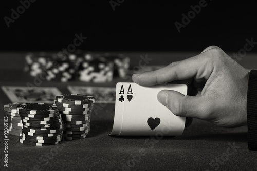 Closeup of poker player with two aces in black and white photo