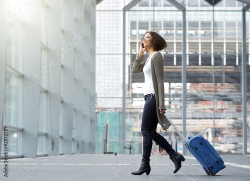 Traveling young woman with mobile phone and suitcase