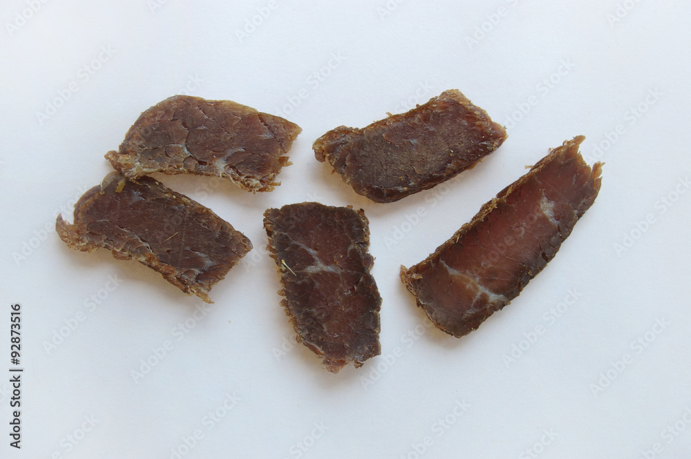Biltong snack piled up on white paper Biltong snack piled up on white paper