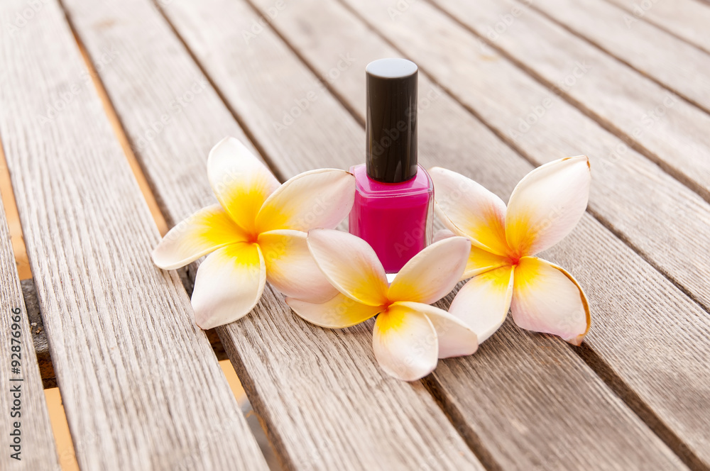 Fuchsia nail polish in the bottle and flowers on the woody background Fuchsia nail polish in the bottle and flowers on the woody background