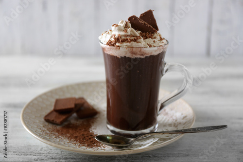 Cup of coffee with cream on color wooden background