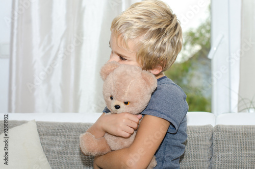 Junge kuschelt mit Teddy photo