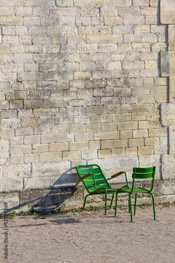 Fototapeta premium Stone wall and two green chairs in Tuileries Garden (Vertical)