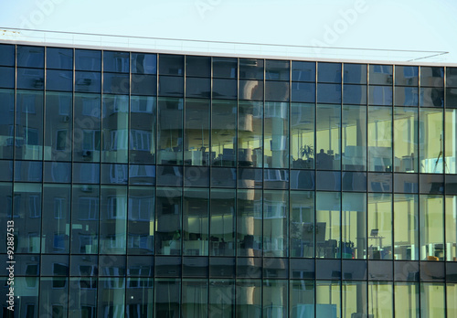 Office work places behind the windows of business center building