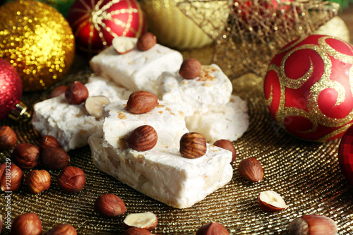 Sweet nougat with hazelnuts and Christmas decoration table close up