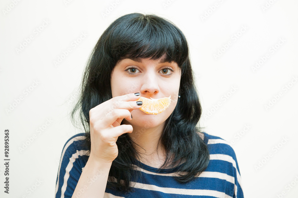 Smiling brunette girl plays with orange slice Smiling brunette girl plays with orange slice