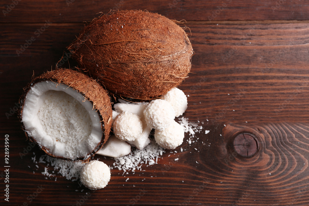 Candies in coconut flakes and fresh coconut on dark wooden background Candies in coconut flakes and fresh coconut on dark wooden background