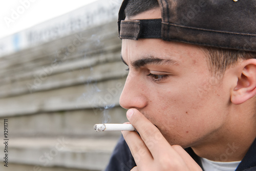 Teenage boy smoking cigarette outdoor. Concept of young people w