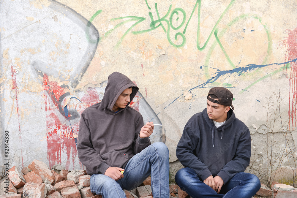 two street hooligans or rappers standing against a graffiti pain two street hooligans or rappers standing against a graffiti pain