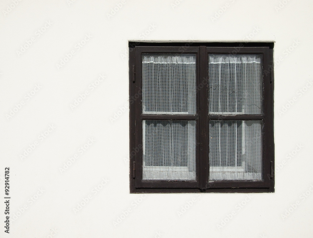 Old black wooden window with curtain on a white facade. Old black wooden window with curtain on a white facade.