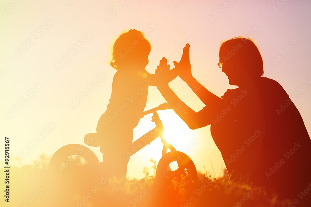 Fototapeta premium father and daughter having fun riding bike at sunset