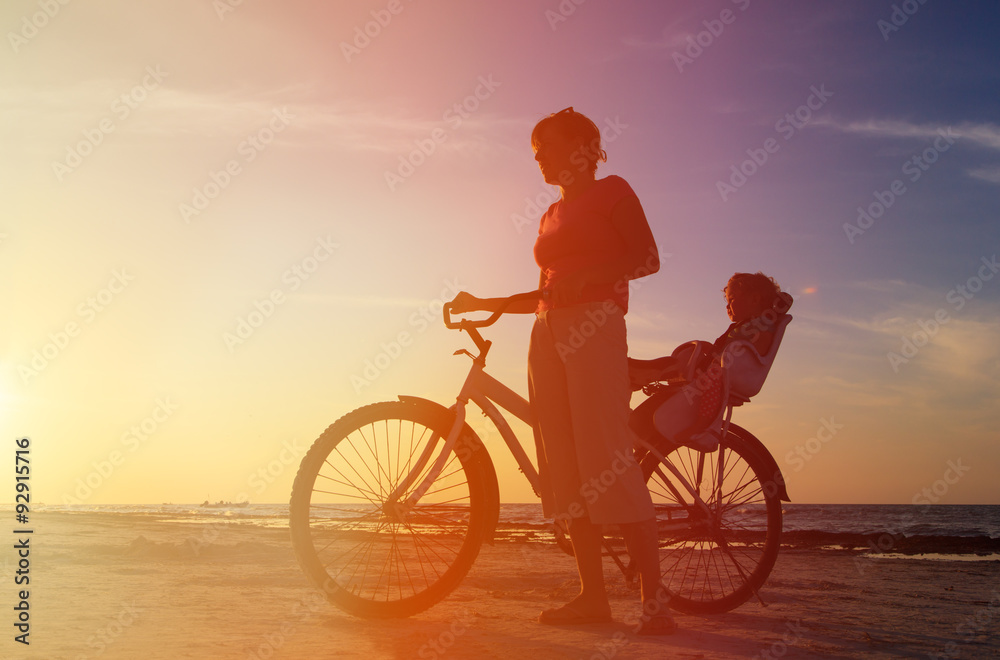 Obraz premium Silhouette of mother and baby biking at sunset