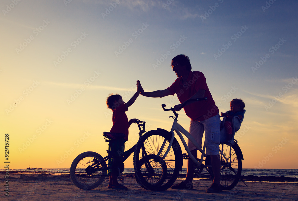 Obraz premium father with two kids on bikes at sunset