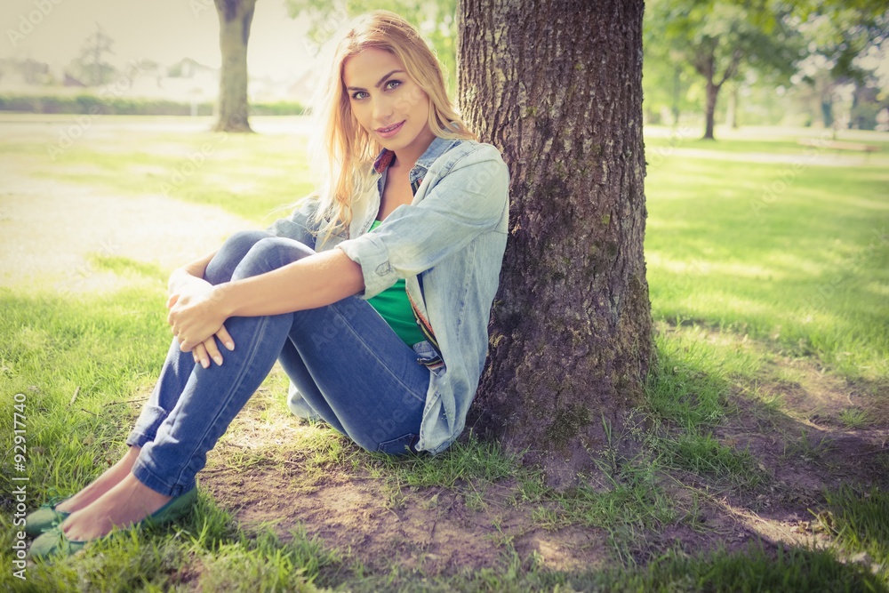 Obraz premium Full length portrait of smiling woman sitting under tree 