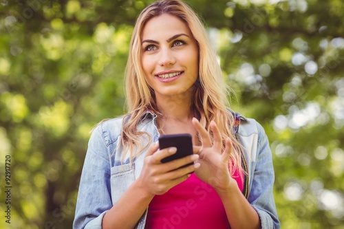 Smiling woman looking away while touching smartphone 