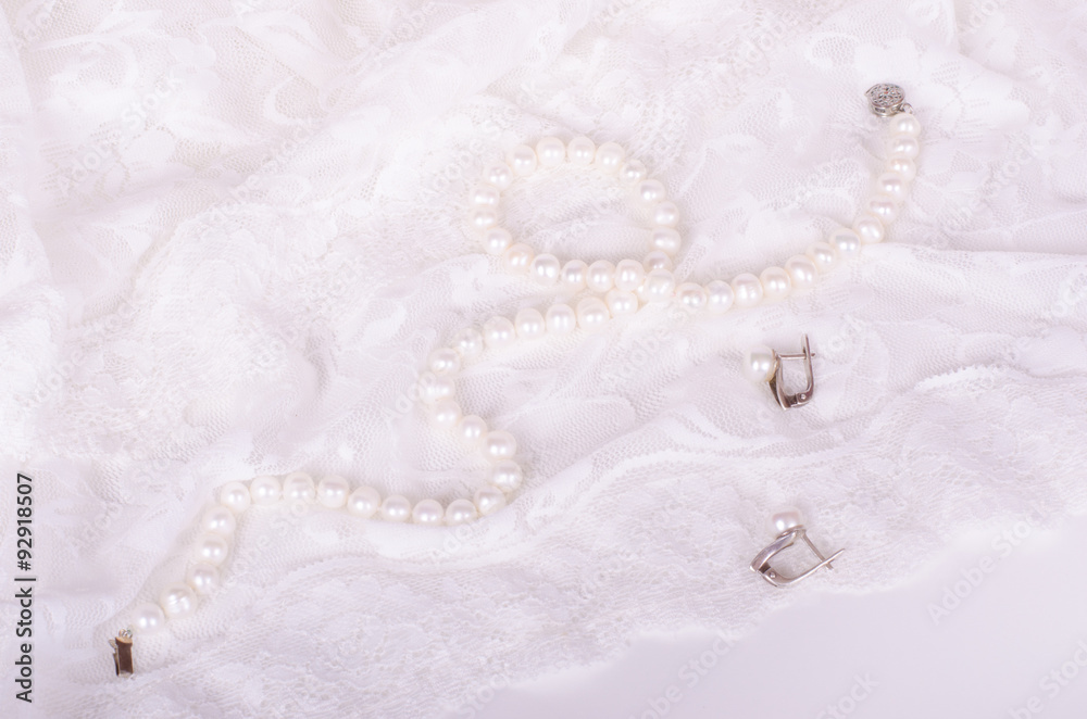 Pearl necklace and earrings on white lace cloth Pearl necklace and earrings on white lace cloth