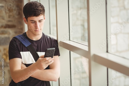 Male student using mobile phone in college