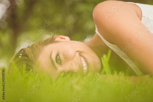 Side view of beautiful happy woman lying on grass 